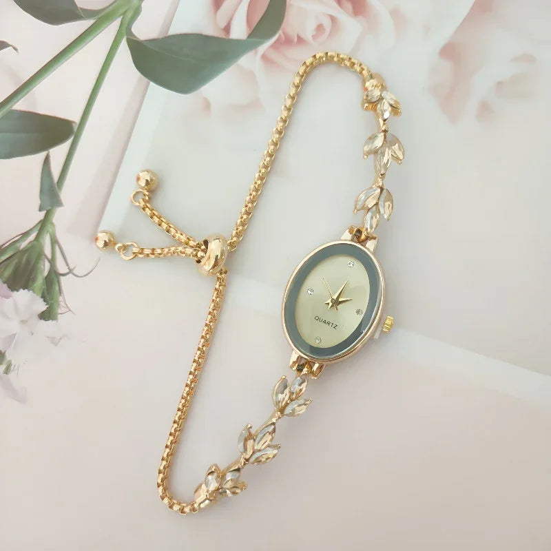 Elegant gold bracelet watch with oval face and leaf-shaped embellishments on a floral background