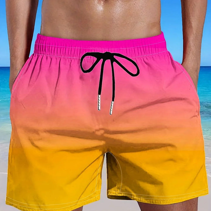 Men's pink to yellow gradient swim shorts with black drawstring at the beach