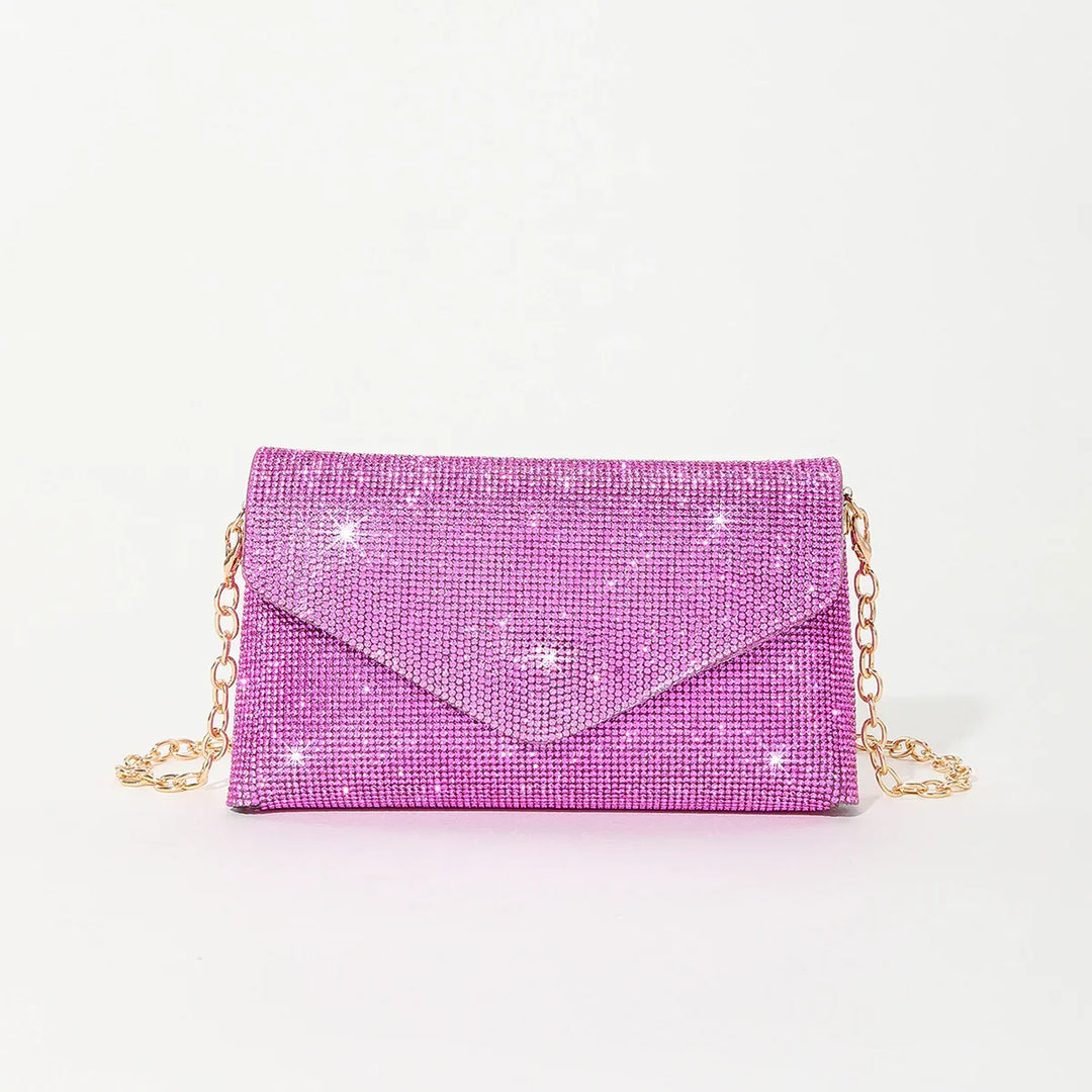 Shiny pink rhinestone clutch bag with gold chain strap on white background