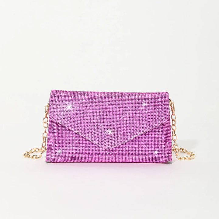 Shiny pink rhinestone clutch bag with gold chain strap on white background