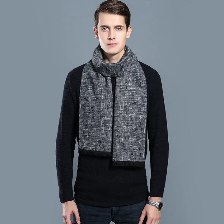 Young man wearing black sweater and gray patterned winter scarf on gray background