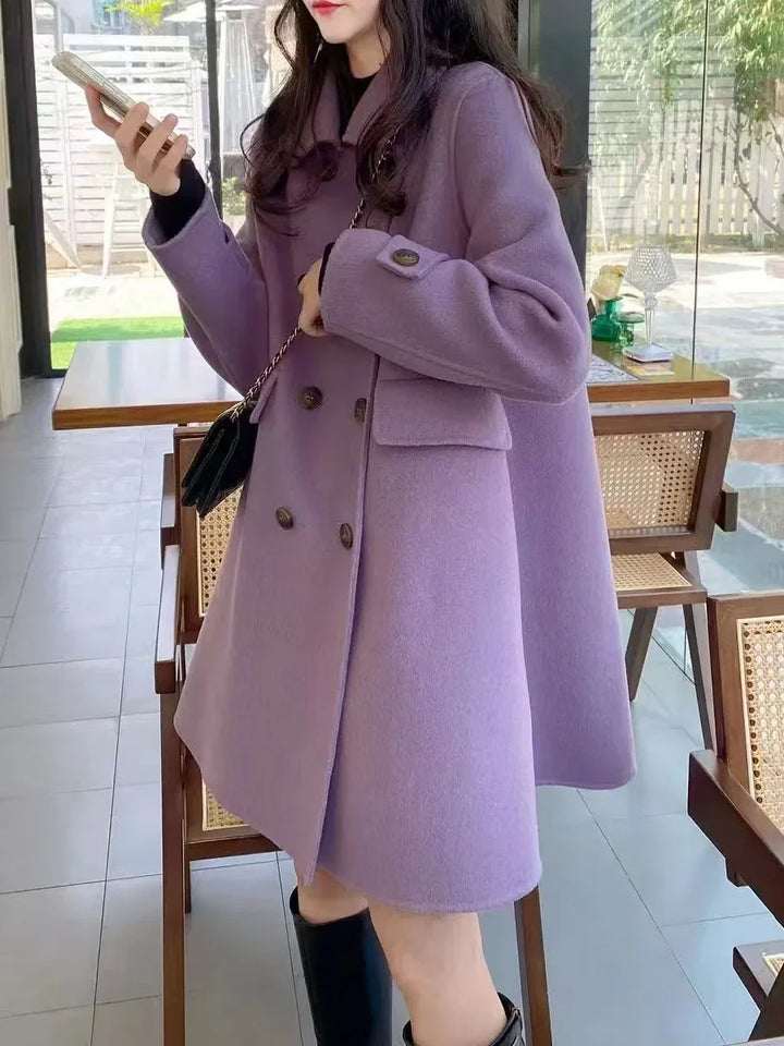 Woman wearing a stylish lavender double-breasted wool coat with black boots in a modern café
