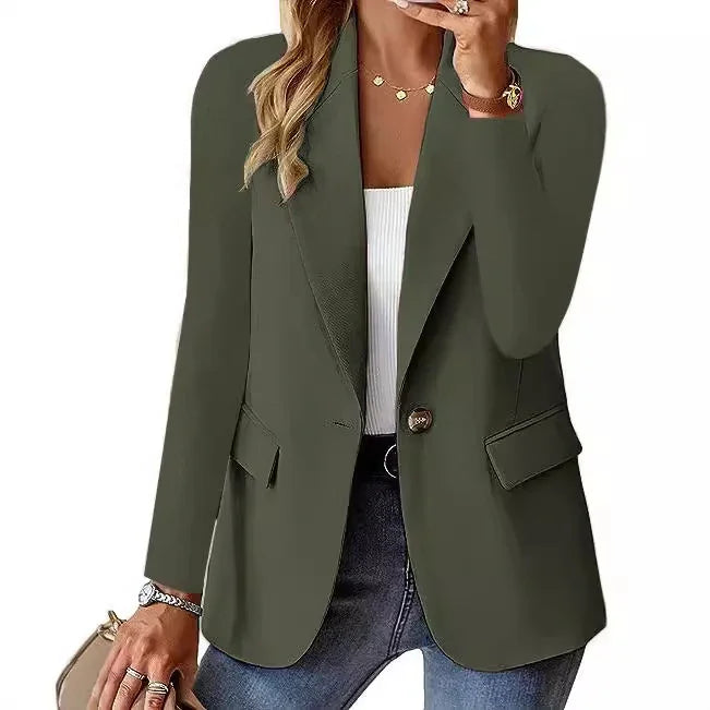 Woman wearing olive green single-button blazer with flap pockets over white top and blue jeans