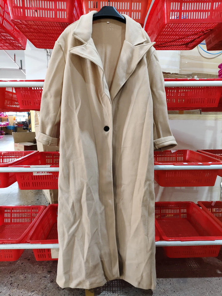 Beige long coat with black button on hanger against red plastic baskets in store