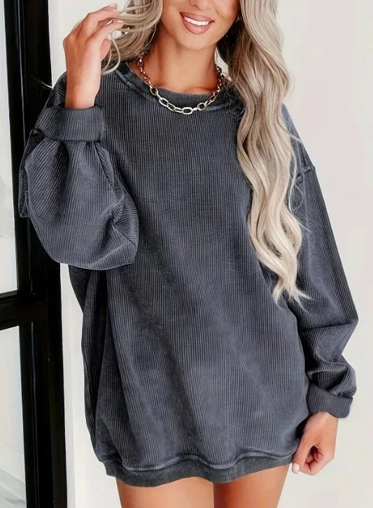 Woman wearing oversized dark gray ribbed long sleeve sweatshirt with chain necklace