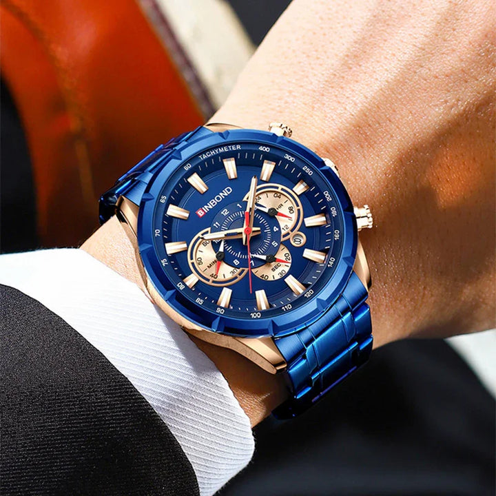 Close-up of a blue and gold BINBOND tachymeter wristwatch on a suit sleeve