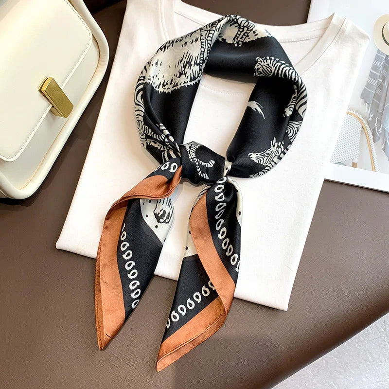Black and brown silk scarf with zebra print over white folded shirt beside white handbag