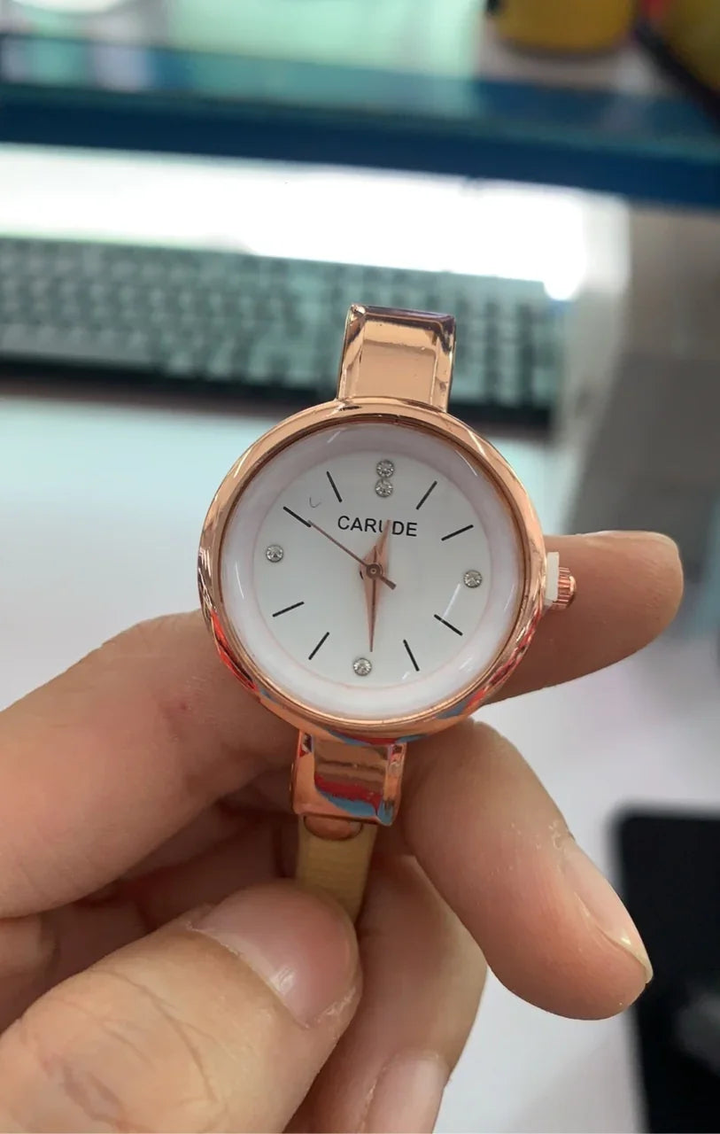 Close-up of hand holding rose gold CARUDE wristwatch with white dial and crystal hour markers