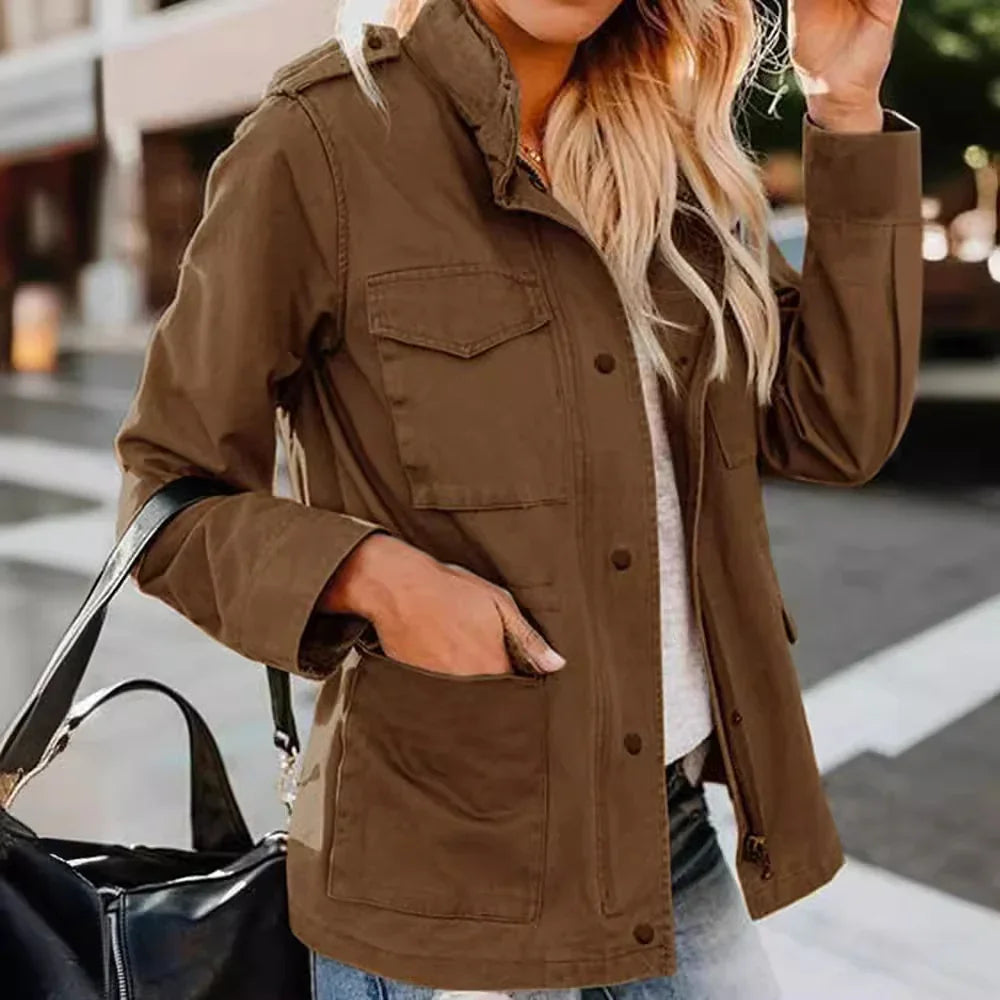 Woman wearing brown utility jacket with flap pockets and carrying black handbag outdoors
