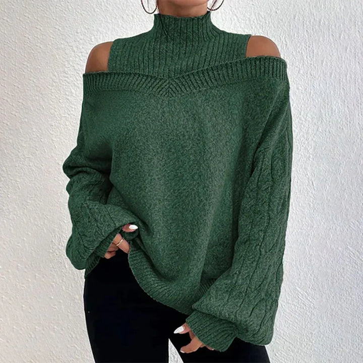 Woman wearing a dark green cold shoulder turtleneck sweater with cable knit sleeves and black pants