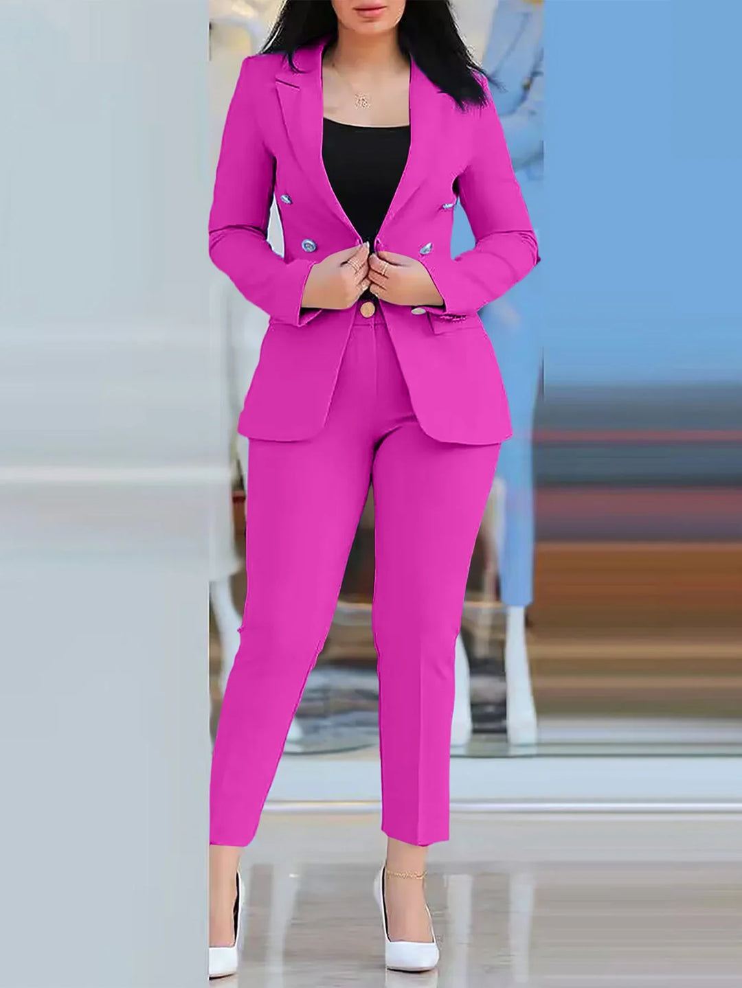 Woman wearing vibrant pink tailored blazer and pants with black top and white heels in indoor setting