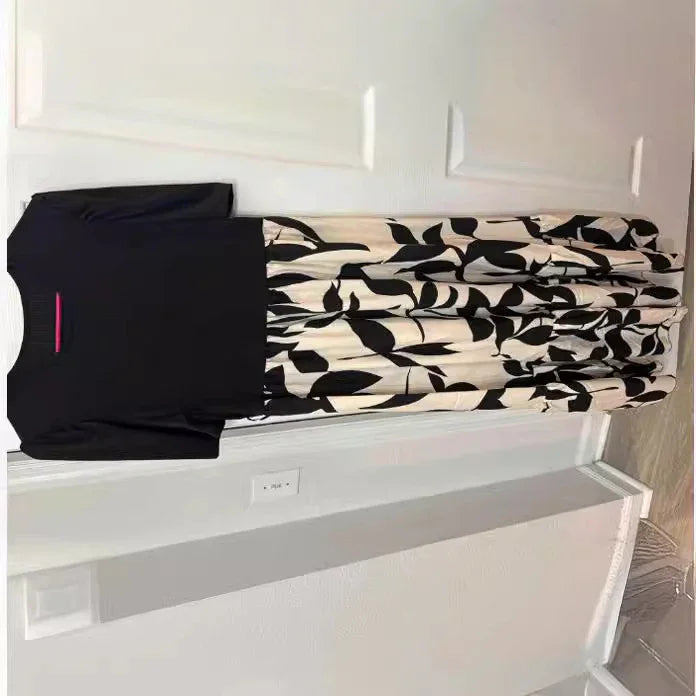 Black short-sleeve top dress with a flowing white skirt featuring bold black leaf patterns hanging on a white door