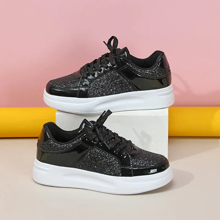 Black glitter and patent leather sneakers with white soles on white block and yellow background