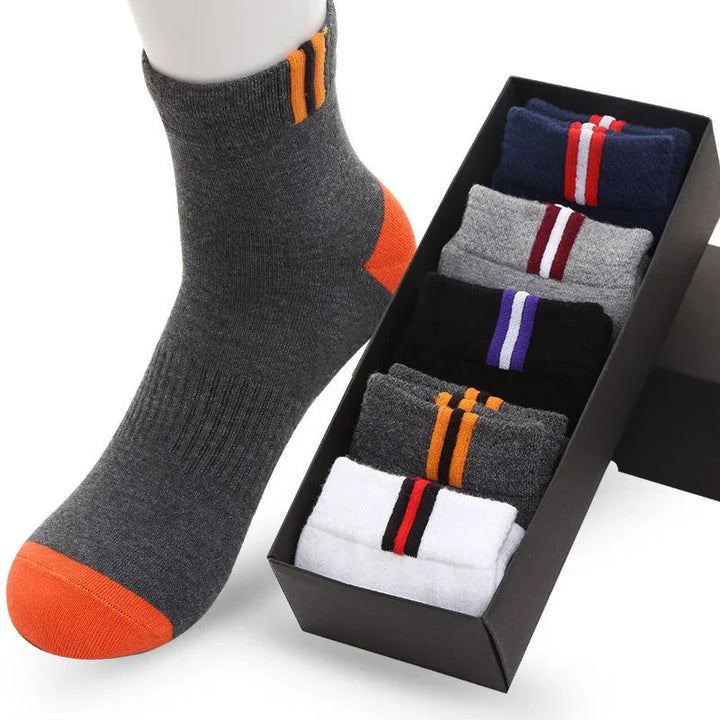 Box of five pairs of colorful striped ankle socks with one gray and orange sock displayed on mannequin foot