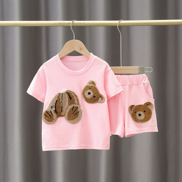 Pink toddler outfit with teddy bear patches on short sleeve tee and shorts hanging on wooden hangers