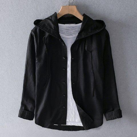 Black button-up hooded shirt layered over white t-shirt on wooden hanger against gray wall