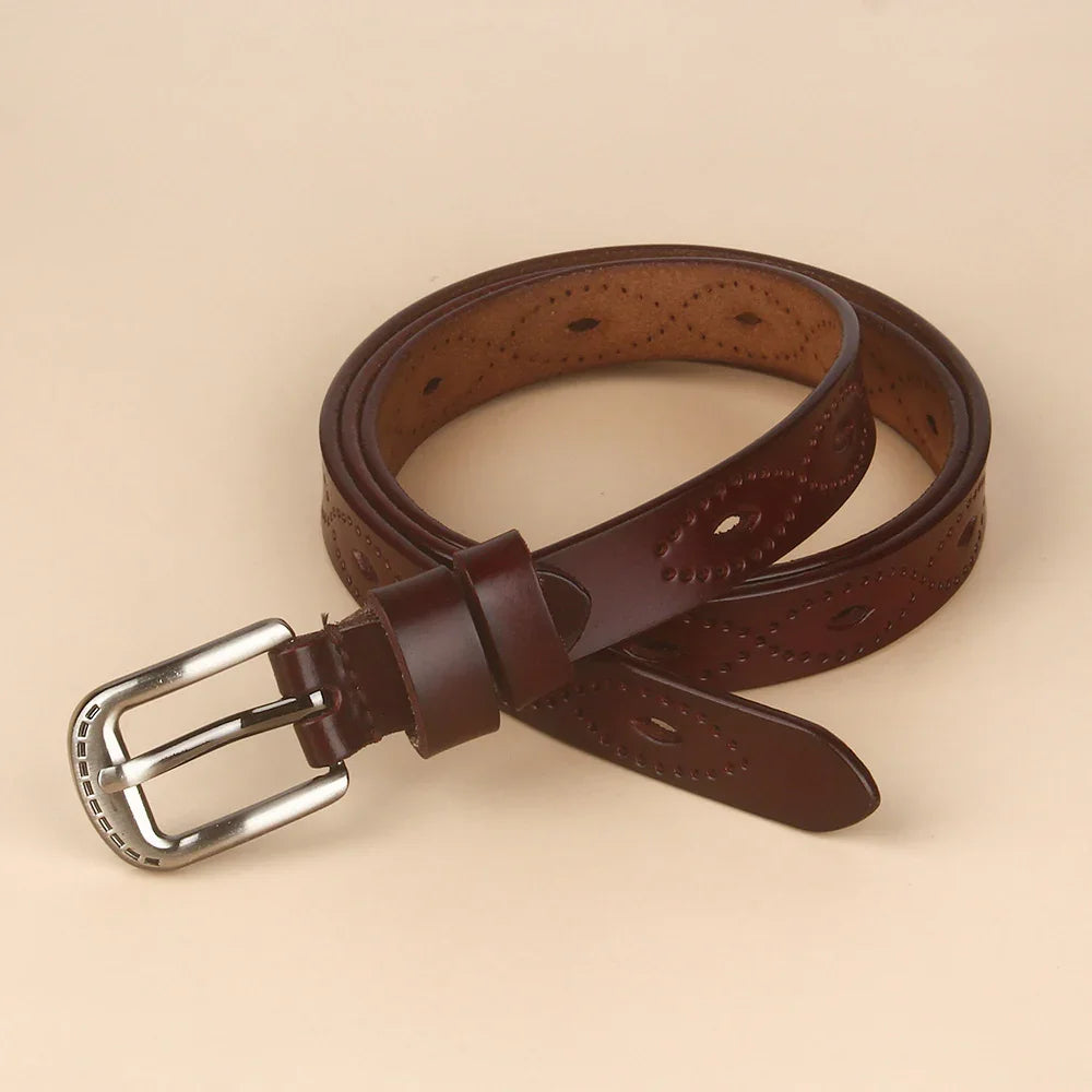 Rolled brown leather belt with decorative perforated patterns and silver buckle on beige background