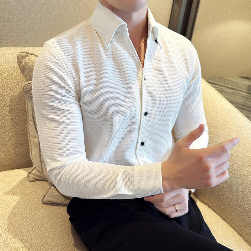 man wearing white textured long-sleeve dress shirt with black buttons sitting on beige couch