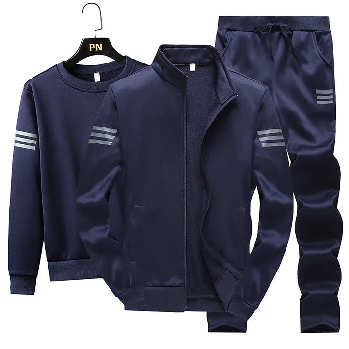 Navy blue men's sportswear set with zip-up jacket, sweatshirt, and drawstring pants featuring silver stripe accents