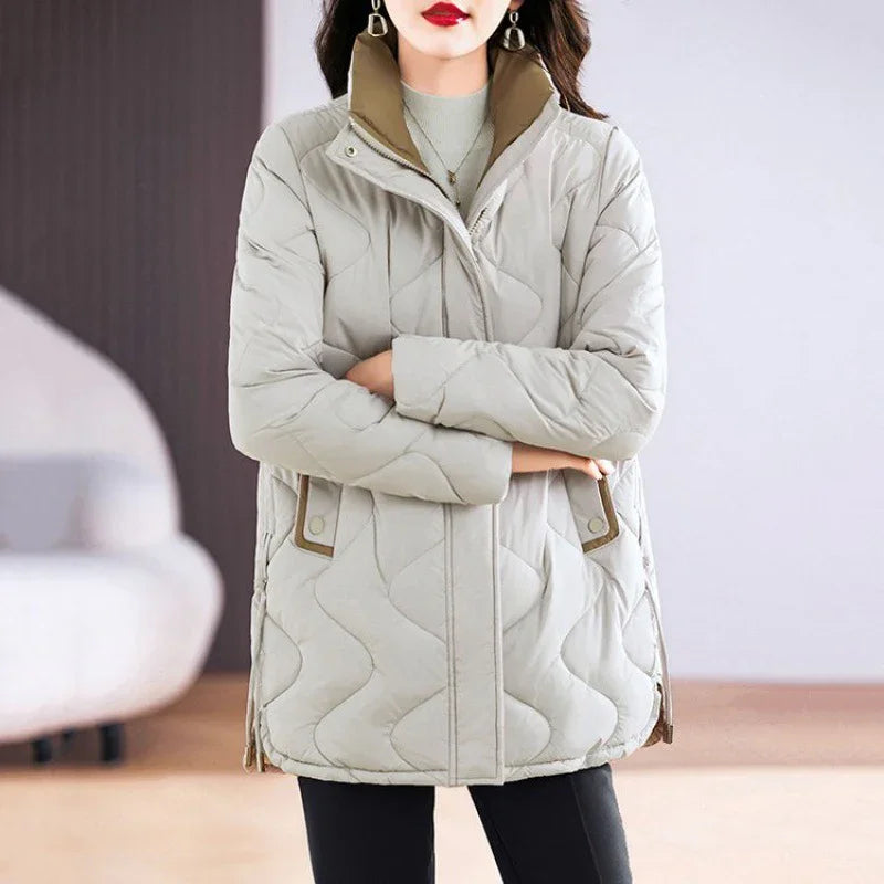 Woman wearing stylish light gray quilted winter jacket with high collar and side pockets