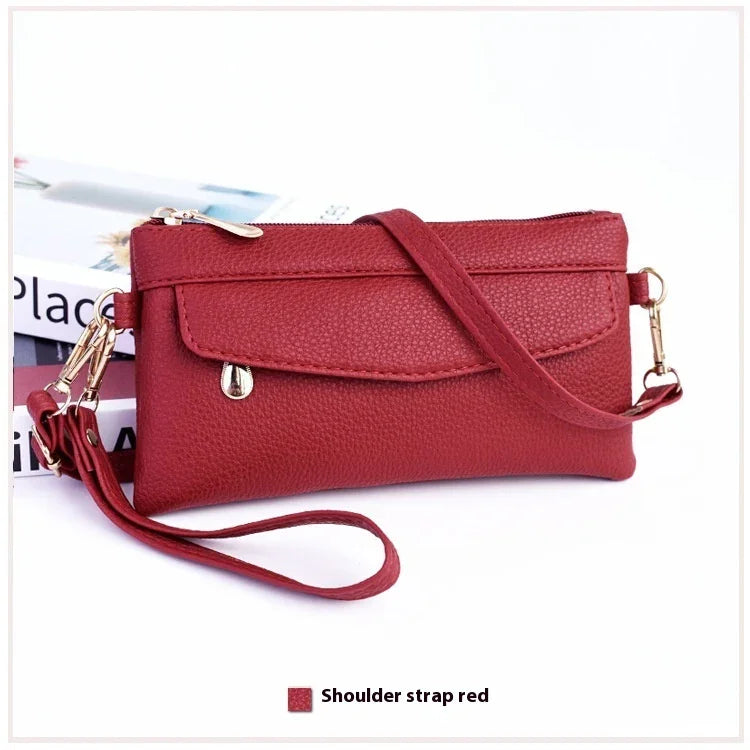 Red textured leather wristlet clutch bag with gold-tone zipper and detachable shoulder strap