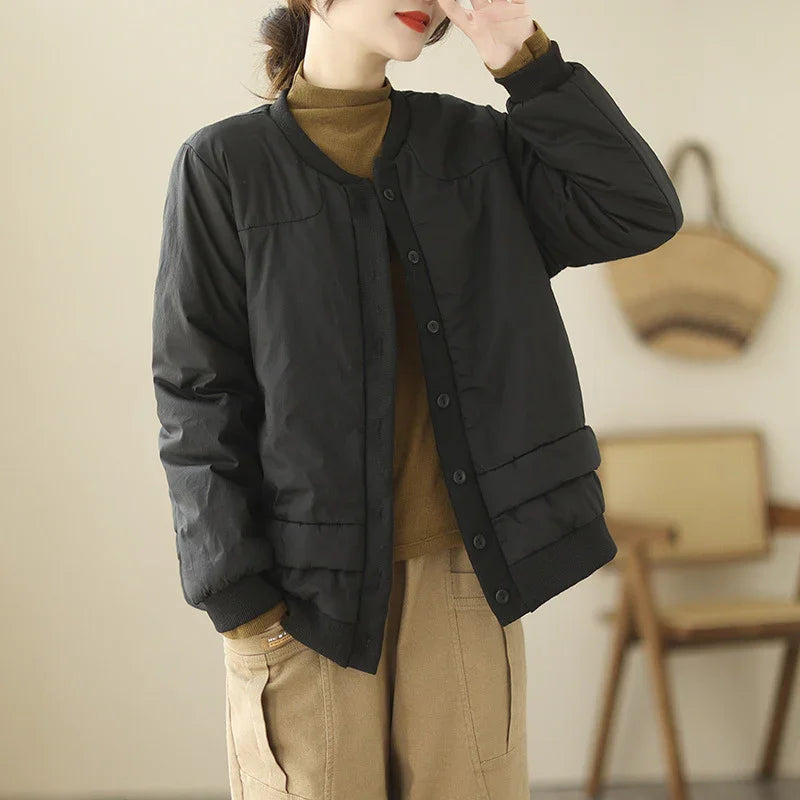 Woman wearing black padded jacket over brown turtleneck sweater and beige cargo pants indoors