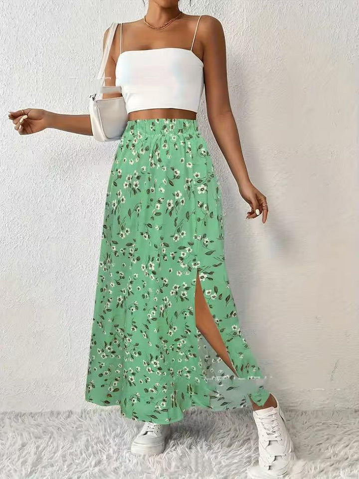 Woman wearing white crop top and green floral slit skirt with white sneakers and handbag