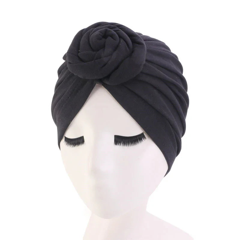 Black turban headwrap with rose detail on a white mannequin head with long eyelashes