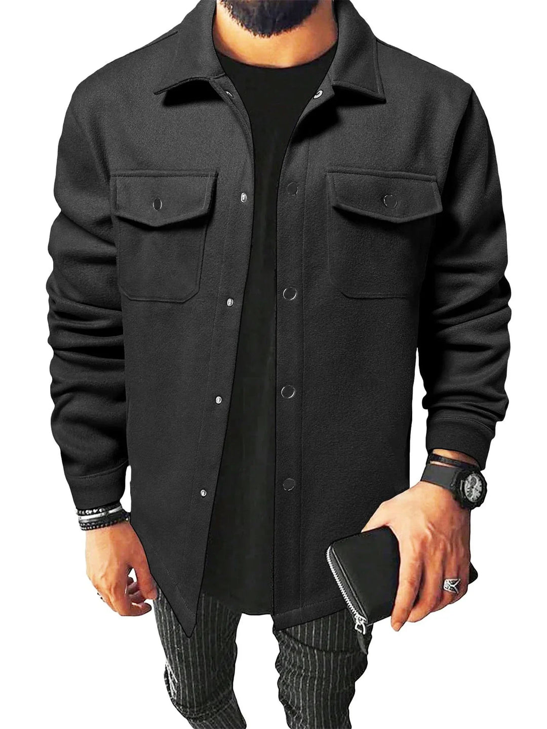 Man wearing black button-up jacket with chest pockets, black shirt, watch, rings, and holding a black wallet