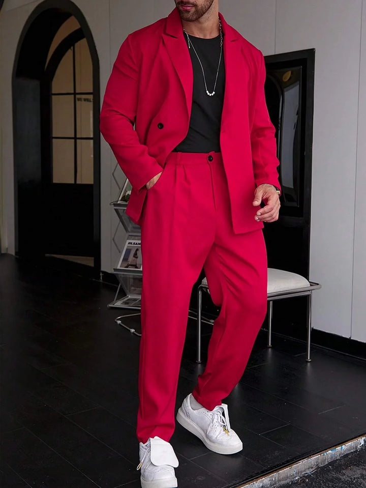 Man wearing bright red suit with black shirt and white sneakers in modern indoor setting