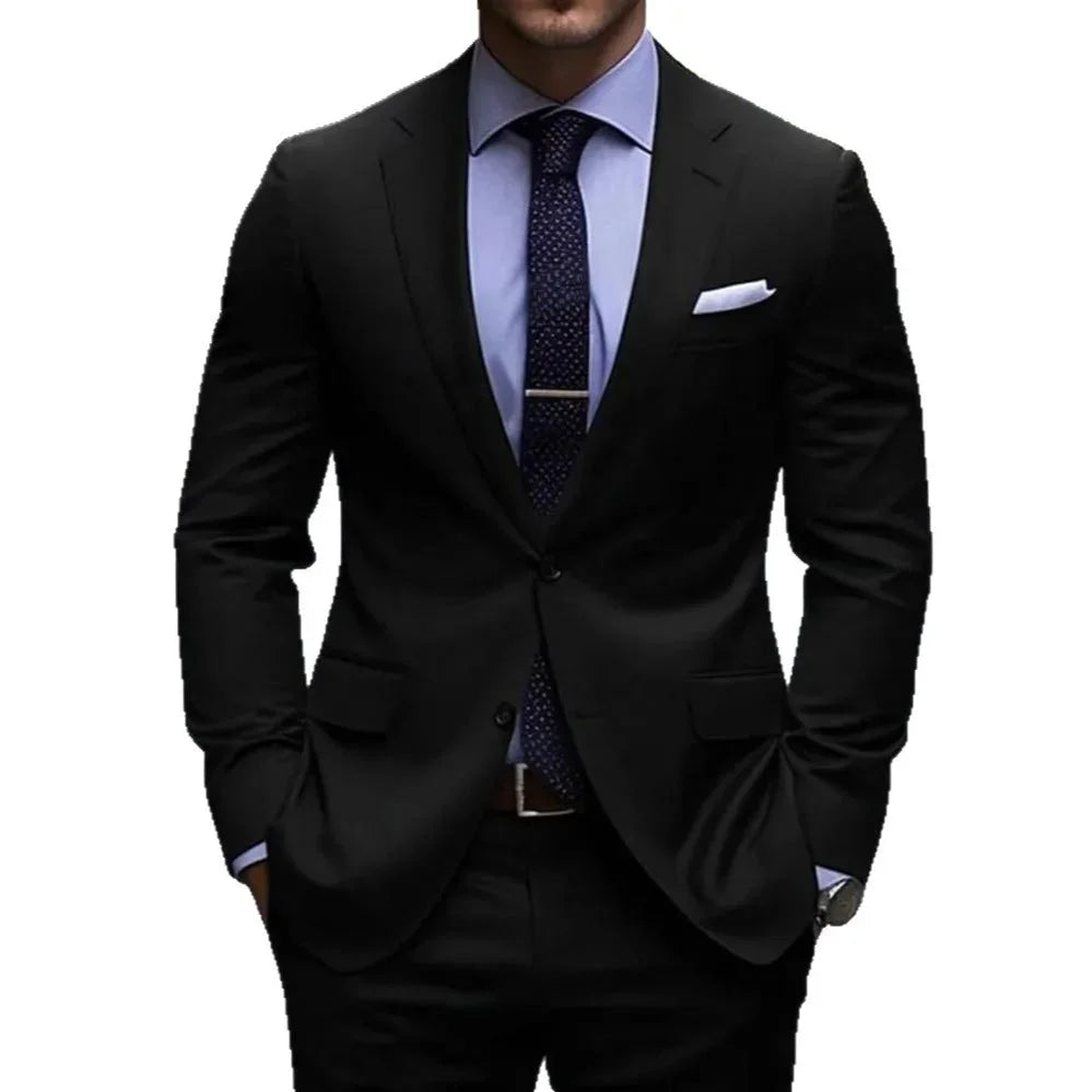 Man wearing black suit with blue dress shirt, navy patterned tie, and white pocket square