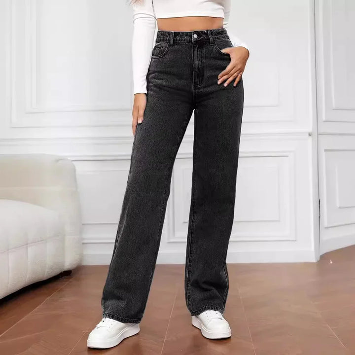 Woman wearing high-waisted black wide-leg jeans with white sneakers and a cropped long-sleeve top