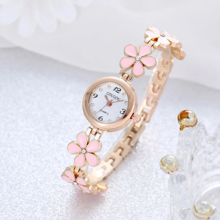 Rose gold ladies watch with pink flower links and crystal accents on silver surface
