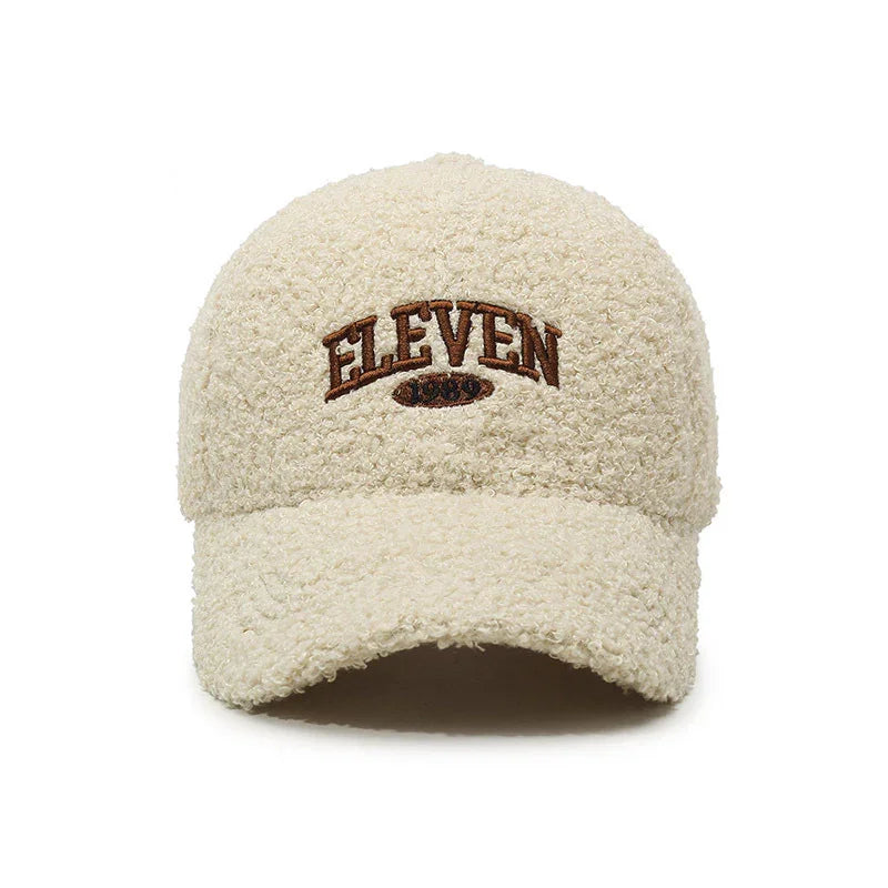 Beige fluffy textured baseball cap with brown embroidered text ELEVEN 1990 on front