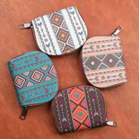 Four small zippered coin purses with colorful geometric tribal patterns on a brown background