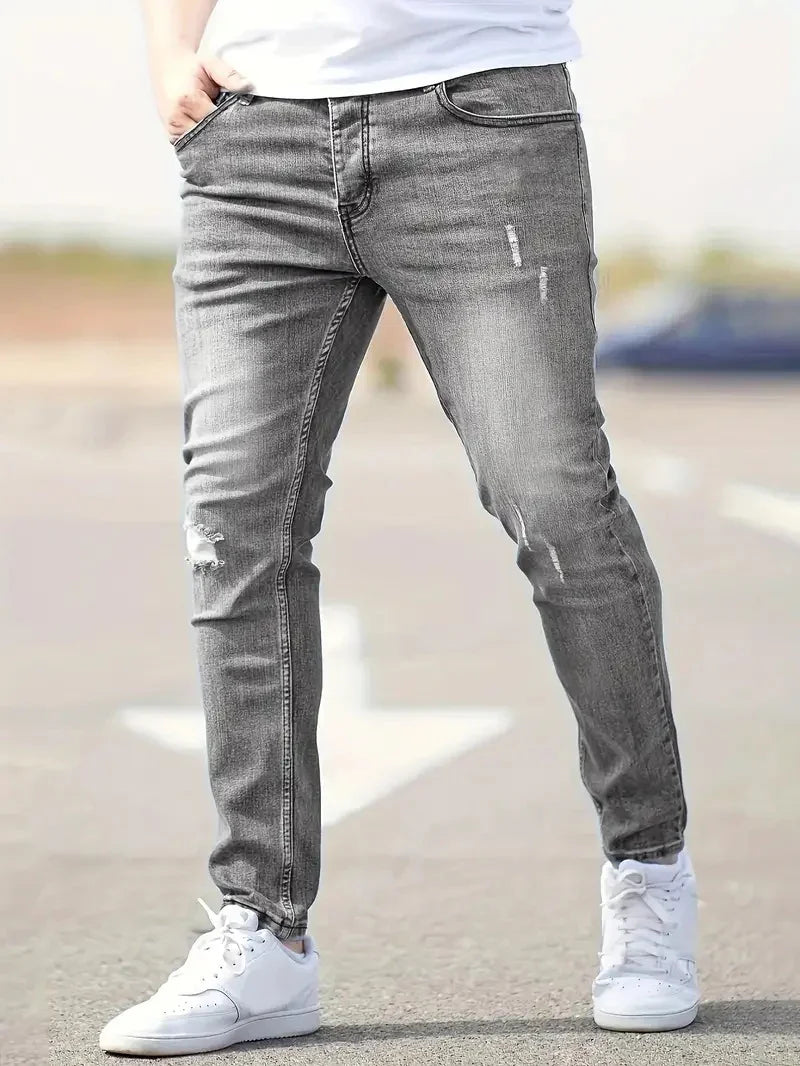 Casual gray distressed slim fit jeans worn with white sneakers and a white shirt outdoors