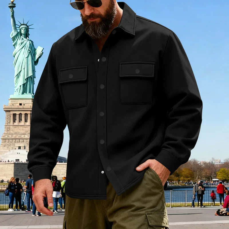 Bearded man wearing black button-up shirt and sunglasses near Statue of Liberty on sunny day