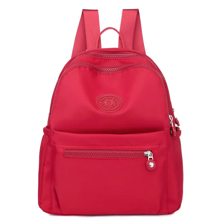 Red compact nylon backpack with front zip pocket and adjustable shoulder straps