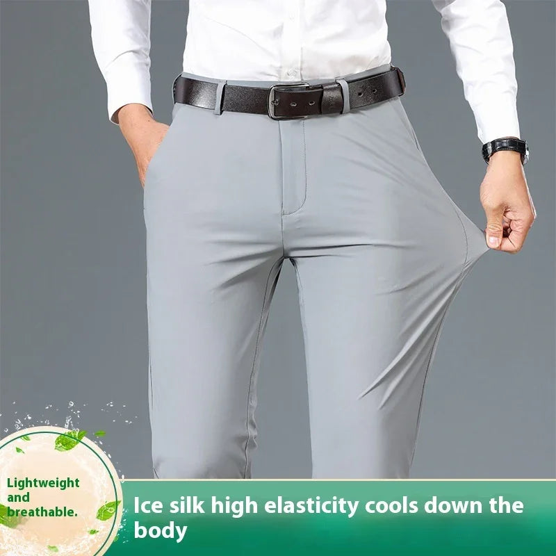Man wearing light grey stretchy ice silk pants with black belt and white shirt, demonstrating fabric elasticity