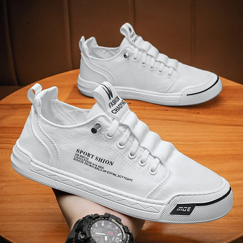 White casual sneakers with black text accents on wooden table, sporty streetwear style shoes