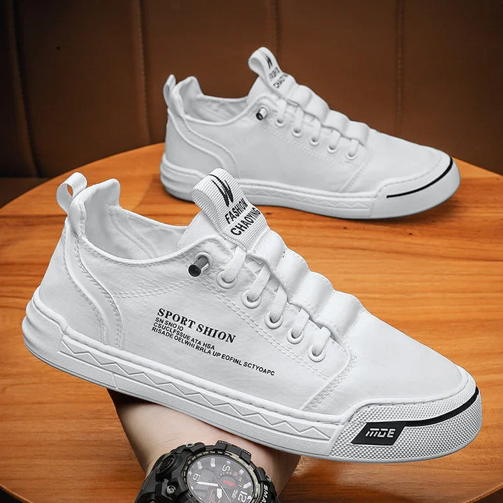 White casual sneakers with black text accents on wooden table, sporty streetwear style shoes