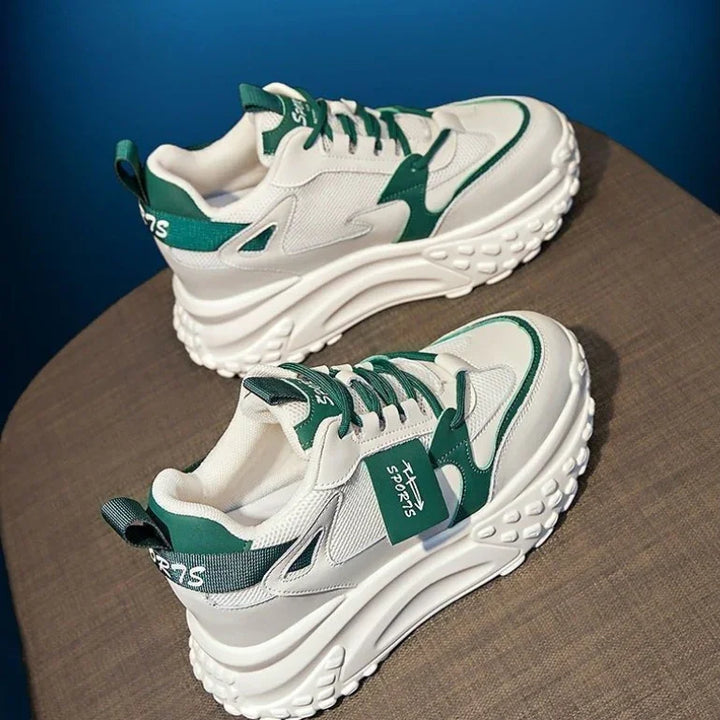 White and green chunky sole sneakers with thick textured outsole on brown surface