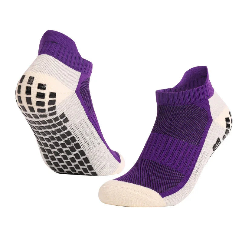 Pair of purple and white low-cut grip socks with black anti-slip soles on white background