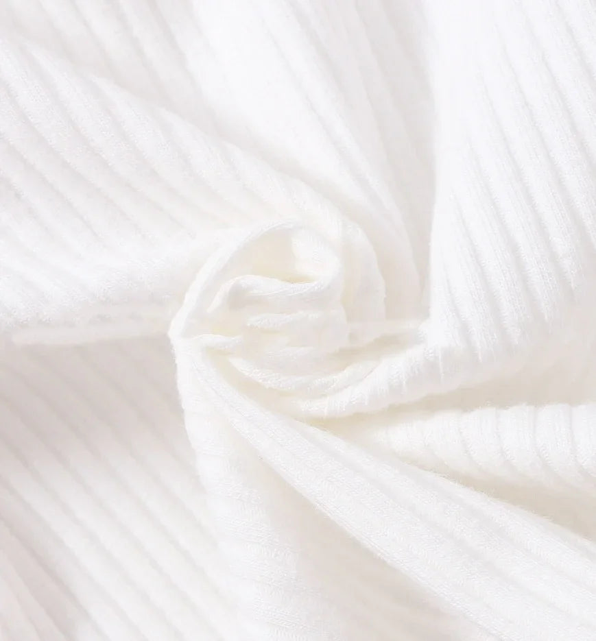 Close-up of soft white ribbed fabric texture with gentle folds and swirl pattern