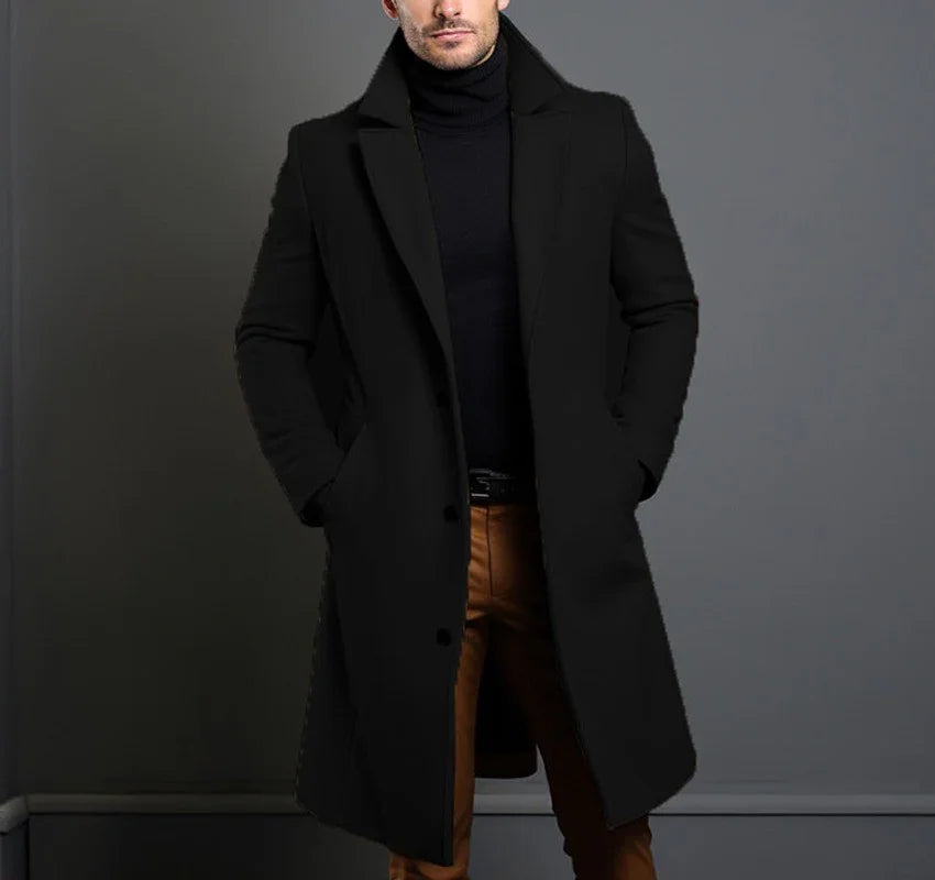 Man wearing stylish black overcoat and black turtleneck with brown pants against gray background