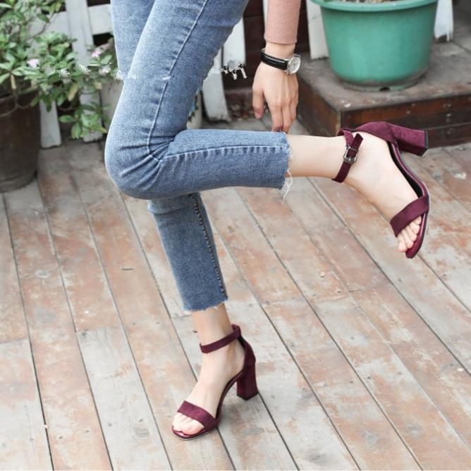 woman wearing burgundy block heel sandals and cropped blue jeans standing on wooden floor