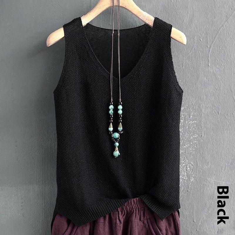 Black sleeveless knitted top with turquoise bead necklace on wooden hanger against gray wall