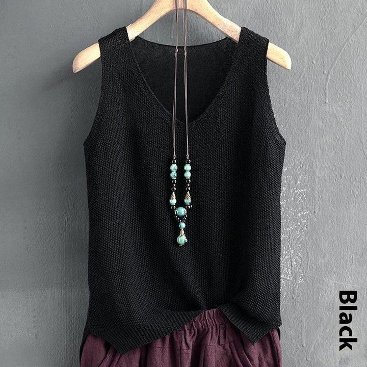 Black sleeveless knitted top with turquoise bead necklace on wooden hanger against gray wall