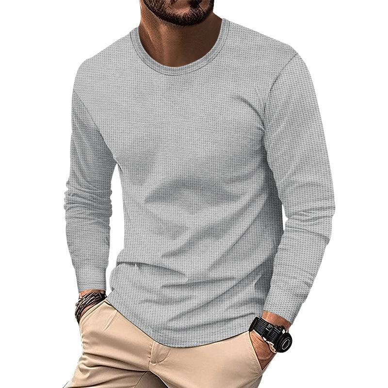 Man wearing light gray textured long sleeve shirt with beige pants and black wristwatch