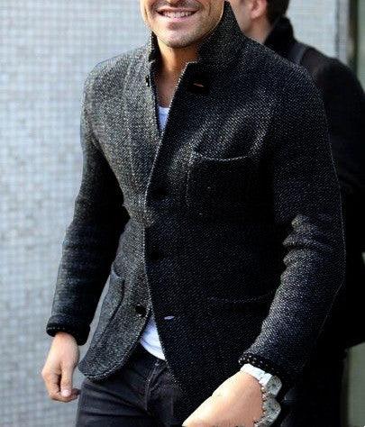Man wearing stylish dark textured blazer over white shirt, smiling with hands by sides
